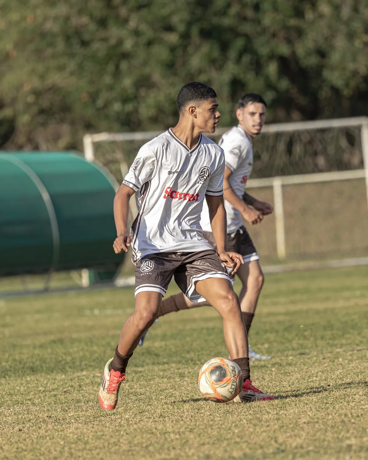 Atleta de uniforme branco domina a bola