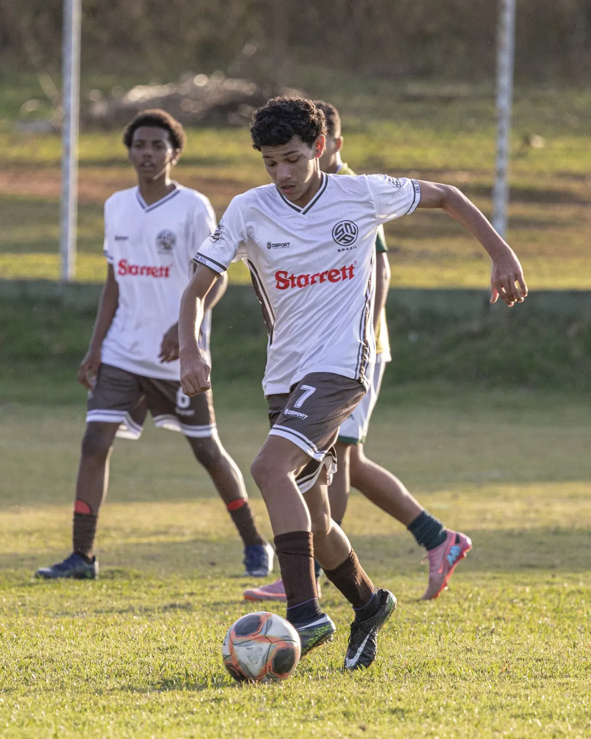 Dois atletas da SNA Brasil, de uniforme branco, disputam a bola