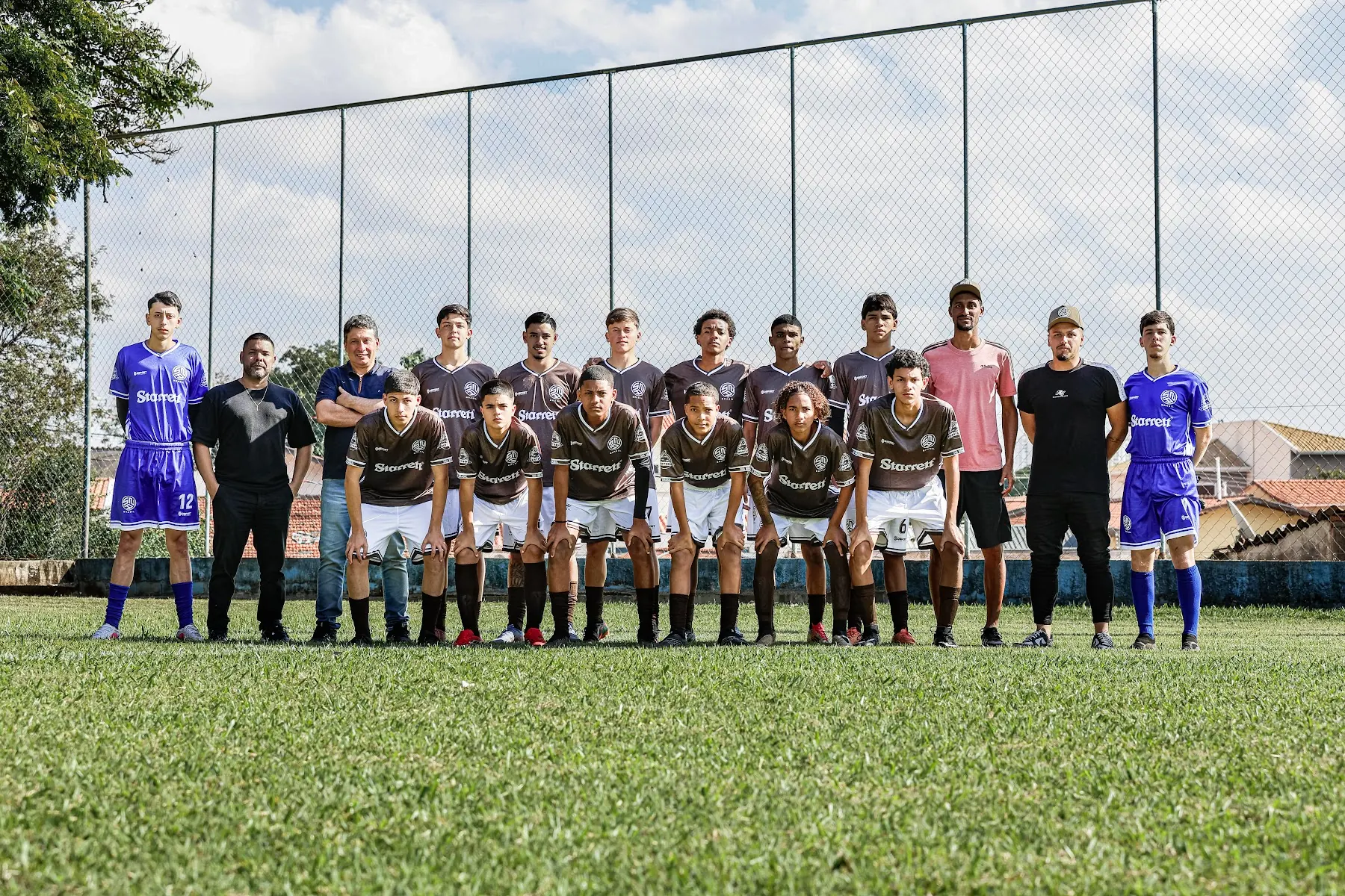Elenco e comissão técnica da SNA Brasil perfilados diante do alambrado