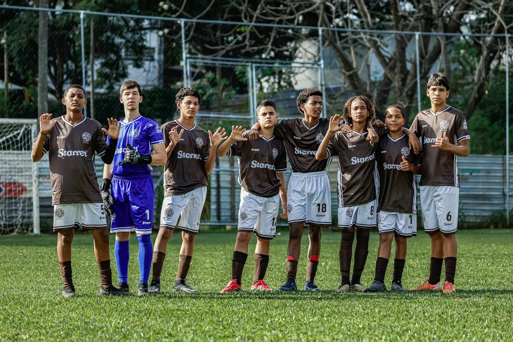 Atletas da SNA Brasil com o uniforme marrom, perfilados no gramado